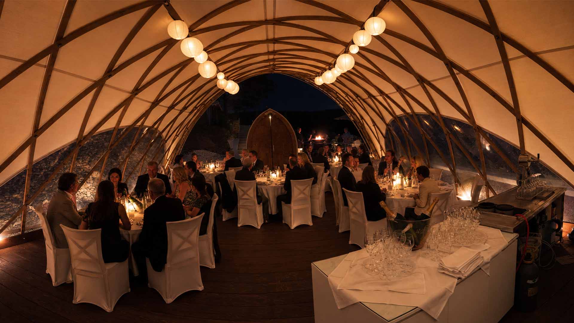 Festlich gedeckte Tafel im beleuchteten Eventzelt des Restaurant Harzfenster, Gäste bei einem Abendessen (KI-generiertes Bild)
