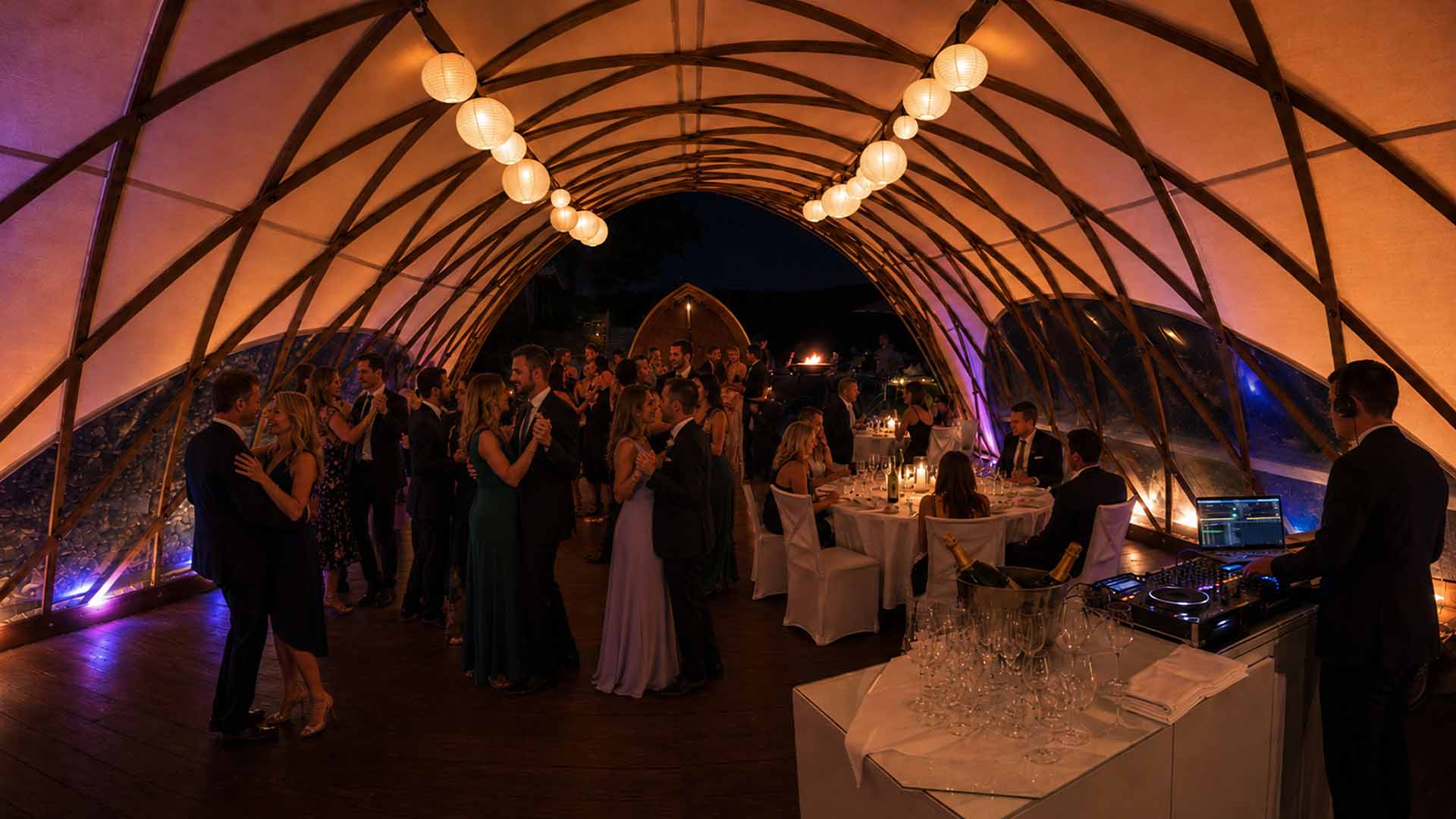Feiernde Gäste tanzen im beleuchteten Eventzelt, im Vordergrund ein DJ-Pult (KI-generiertes Bild)